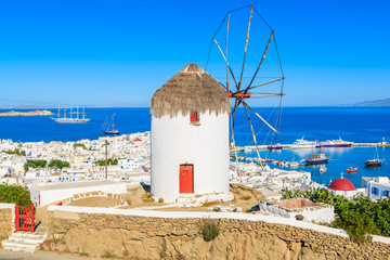 A view of famous traditional windmill overlooking Mykonos port, island of Mykonos, Cyclades, Greece - obrazy, fototapety, plakaty