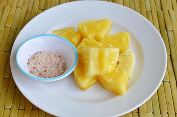 pineapple slice dipping with mixed sugar salt and pepper on white dish