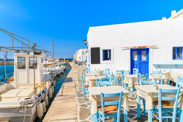 Taverna tables and fishing boats in Naoussa port, Paros island, Greece