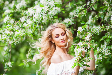 Beautiful bride posing near apple-tree in blossom