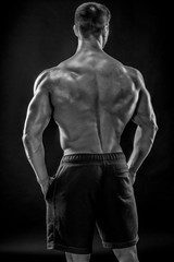 Muscular bodybuilder guy doing posing over black background