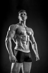 Muscular bodybuilder guy doing posing over black background