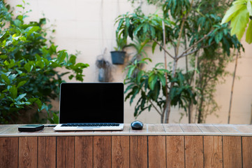Laptop computer mock up with hard disk on wood texture in garden, left of frame. Relax from work.