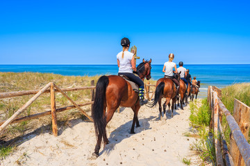 Les jeunes femmes à cheval sur la plage de sable du village côtier de Lubiatowo, mer Baltique, Pologne