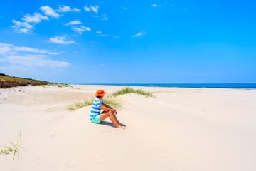 Fototapeta na wymiar Young woman tourist sitting in sand on beautiful beach in Lubiatowo coastal village, Baltic Sea, Poland
