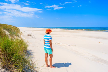 Fototapeta na wymiar A young woman tourist standing on white sand beach, Baltic Sea, Bialogora coastal village, Poland
