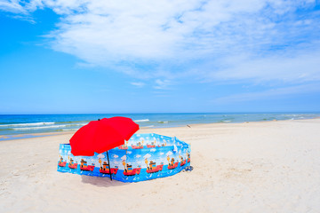 Red umbrella and windbreak on beautiful sandy beach in Leba town, Baltic Sea, Poland