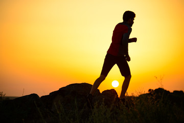 Young Sportsman Running on the Rocky Mountain Trail at Sunset. Active Lifestyle