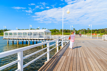 Fototapeta premium Unidentified woman wearing stylish dress walking on Jurata molo on Hel peninsula, Baltic Sea, Poland