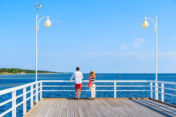Obraz premium Unidentified couple of people standing on pier in Jurata town on Hel peninsula, Baltic Sea, Poland