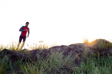 Young Sportsman Running on the Rocky Mountain Trail at Sunset. Active Lifestyle