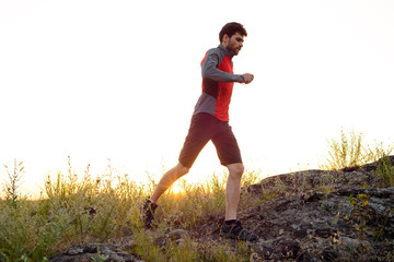 Young Sportsman Running on the Rocky Mountain Trail at Sunset. Active Lifestyle