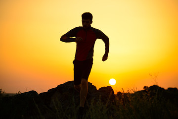 Young Sportsman Running on the Rocky Mountain Trail at Sunset. Active Lifestyle