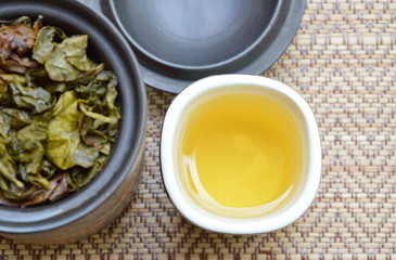 tea cup and leaf in jar on bamboo mat