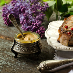In old mustard jar with a silver steak knife and branch of lilac