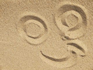 A smiley face drawing on a sand
