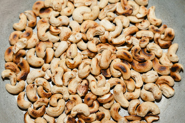 Closeup of roasted cashew on frying pan with selective focus