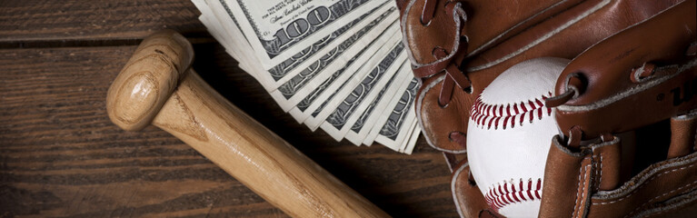 Photo of an Baseball ball, glove, bat and money on wooden table. Studio shot