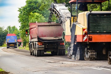 Asphalt removing machine loading powdered asphalt on the truck