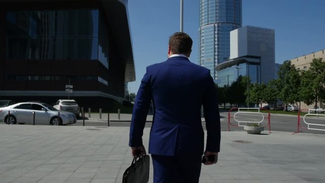 Businessman in suit walking down the street with a briefcase in his hands. 4k