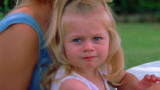 Close-up of a little blond-haired girl looking disapprovingly at the camera