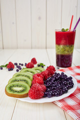 Berry smoothie.Fresh summer cocktail.Blueberry,raspberry,kiwi.Vitamin A. Vitamin C.Checkered napkin.On white wooden table with ingredients.Healthy lifestyle.Diet and weight loss concept.