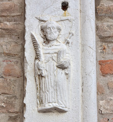 Medieval relief of St Peter of Verona on St John and Paul basilica outside wall, in Venice