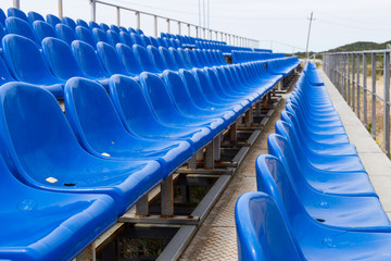 Empty plastic blue chairs at stadium in a row.