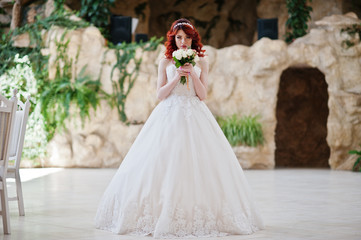 Obraz premium Charming red-haired bride with wedding bouquet at hand posed at