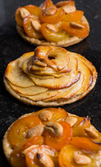 Tart with apricot and apple. Traditional french pie with fruits on dark marble background. Decorated almonds and mint leafs. Delicious dessert with copy space closeup.
