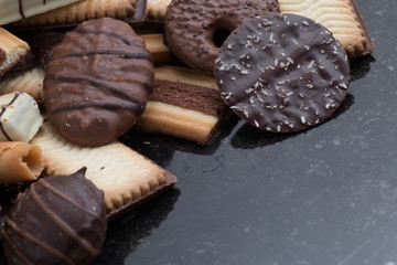 Cookies assorted on black background. Delicious morning snacks for breakfast, brunch and lunch. Appetizing, sweet and fast food.
