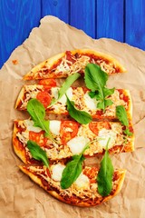 Rucola pizza on wrinkled craft paper with blue background