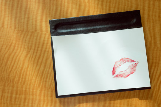 
Sexy girl Red lips kiss on blank white note paper on bed stand table in the morning light. 
romantic message from couple. 
