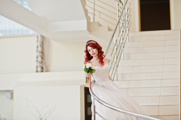 Charming red-haired bride with wedding bouquet at hand posed on