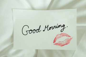 Sexy girl Red lips kiss on blank white note paper on white bed in the morning light. 
romantic message from couple. 