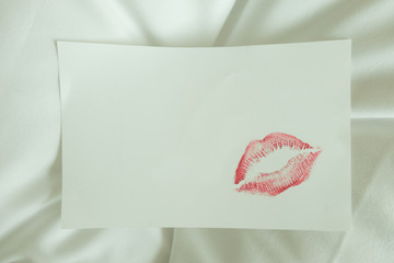 Sexy girl Red lips kiss on blank white note paper on white bed in the morning light. 
romantic message from couple. 