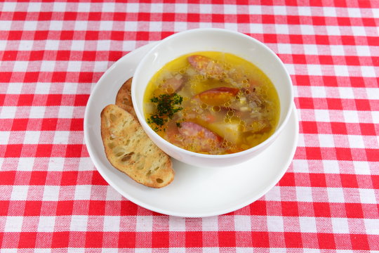 Hot soup with hunting sausages and two slices of bread in a bowl