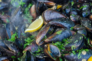 Cooked mussels (Moules Marinieres) in a large bowl with sauce and spices