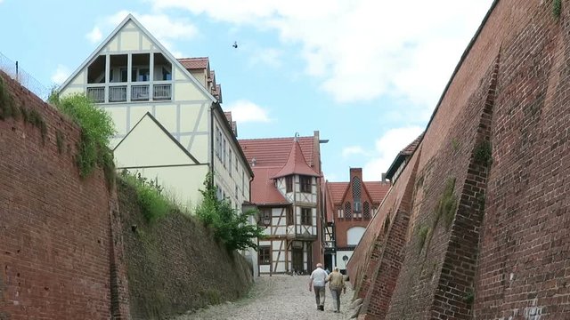 TANGERMUENDE, SAXONY-ANHALT/ GERMANY June 29 2016: Couple walking along the street at town wall of Tangermuende toward the center with its half-timbered houses.