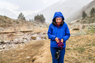 Fototapeta na wymiar Woman hiker trekking in mountains, relaxing standing and looking on first snow falling