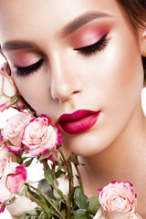 Fototapeta na wymiar Portrait of young beautiful woman with stylish make-up and colorful roses around her face