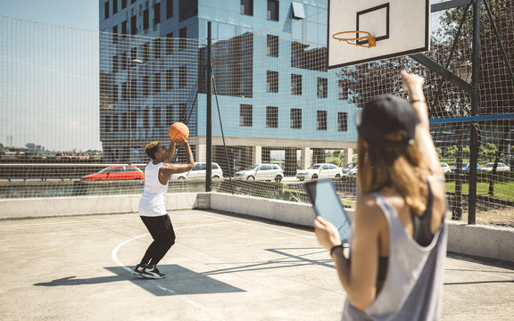 Young woman with digital tablet talking to basketball player