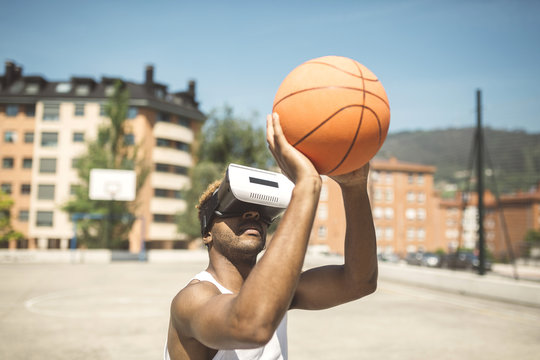 Young man playing basketball with virtual reality glasses on