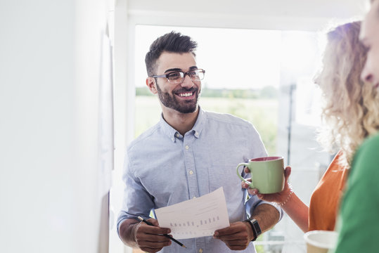 Smiling businessman with colleagues analysing data
