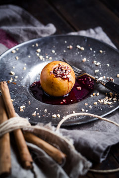 Baked apple with nut- and red jam filling on tin plate