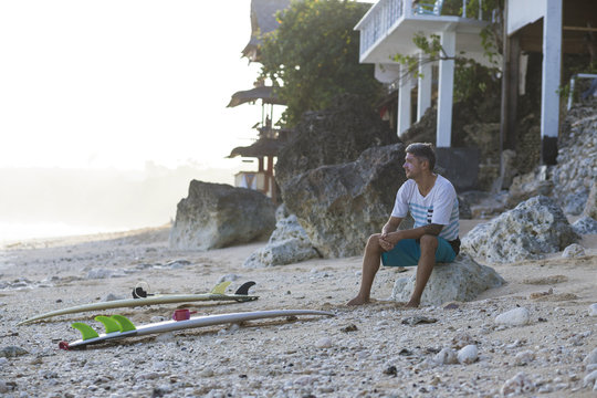 Indonesia, Bali, surfer sitting on the beach