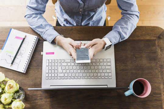 Teenage girl with celll phone and laptop at desk