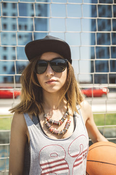 Young woman with cap holding basketball