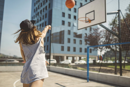 Young woman aiming at basketball hoop