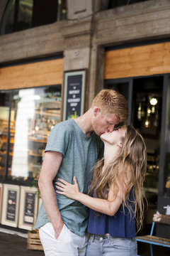 Couple kissing in front of a coffee shop